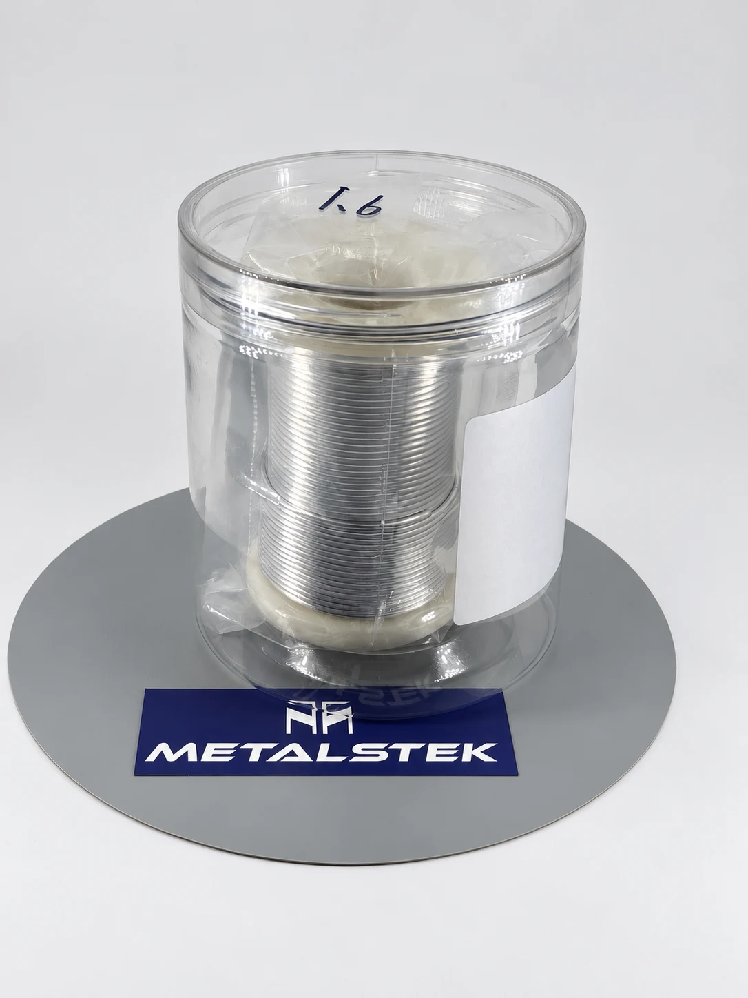 Delivered custom indium wire on a spool inside a clear container, photographed for MetalsTek